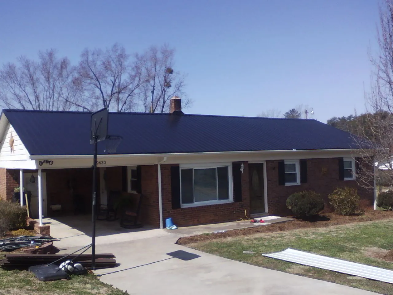 Finished dark blue metal roof on a brick ranch with a carport in Harrisburg